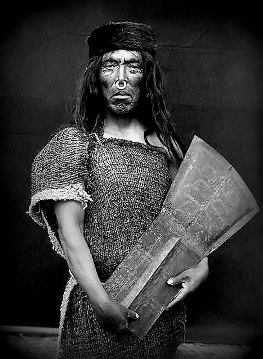 The man belonging to the indigenous Kwakwakawakw group is holding a copper shield-shaped object. 